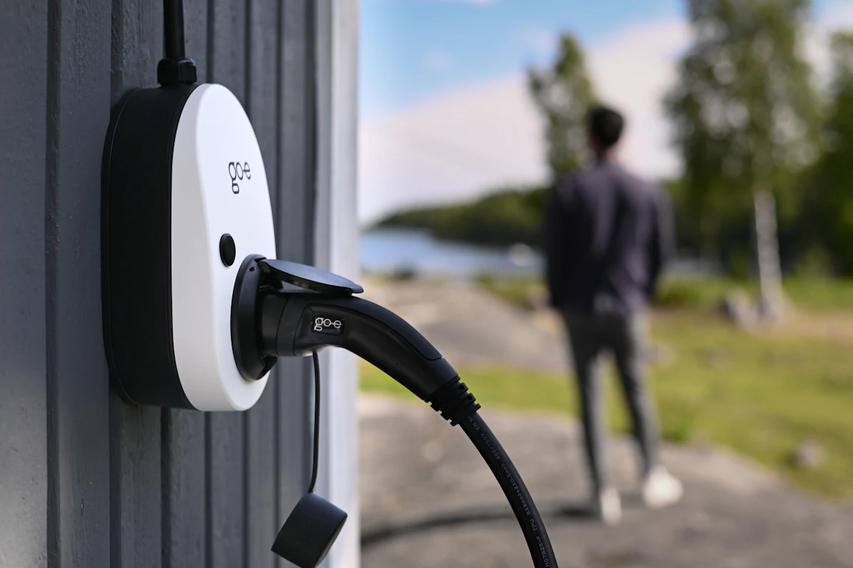 Wallbox mit eingestecktem Ladekabel an der Hauswand